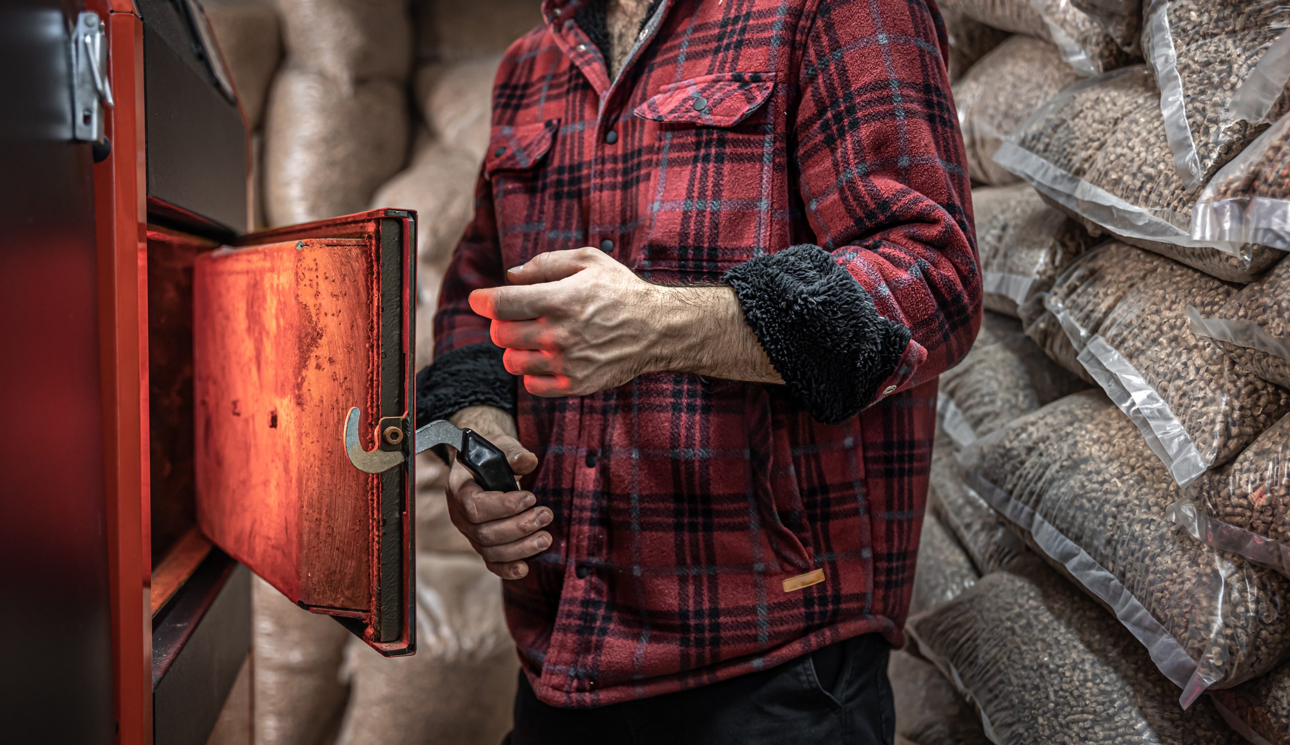 A man in a room with a solid fuel boiler, working on biofuel, economical heating.